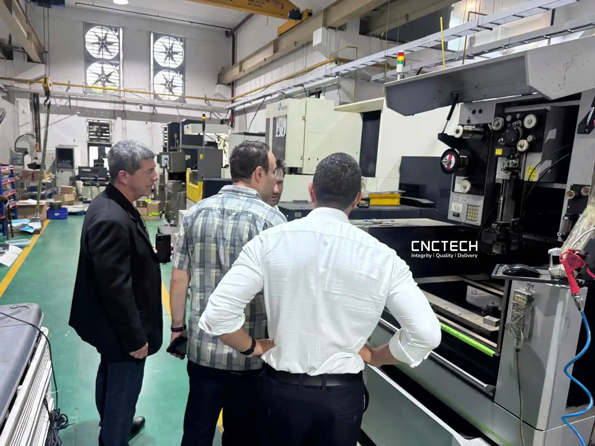 International customers discussing CNC equipment during a visit to CNCTech's manufacturing facility